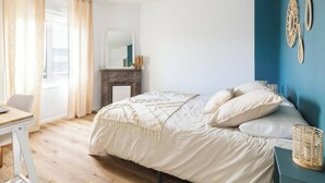 A bedroom with a bed, a desk with a laptop, a mirror, and a blue wall. - Near City Center & Train Station - Saint-Brieuc (Saint-Brieuc)
