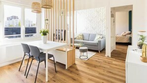 A modern living space with a dining area, a sofa, a bed, and a view of the city. - Near City Center & Train Station - Saint-Brieuc (Saint-Brieuc)