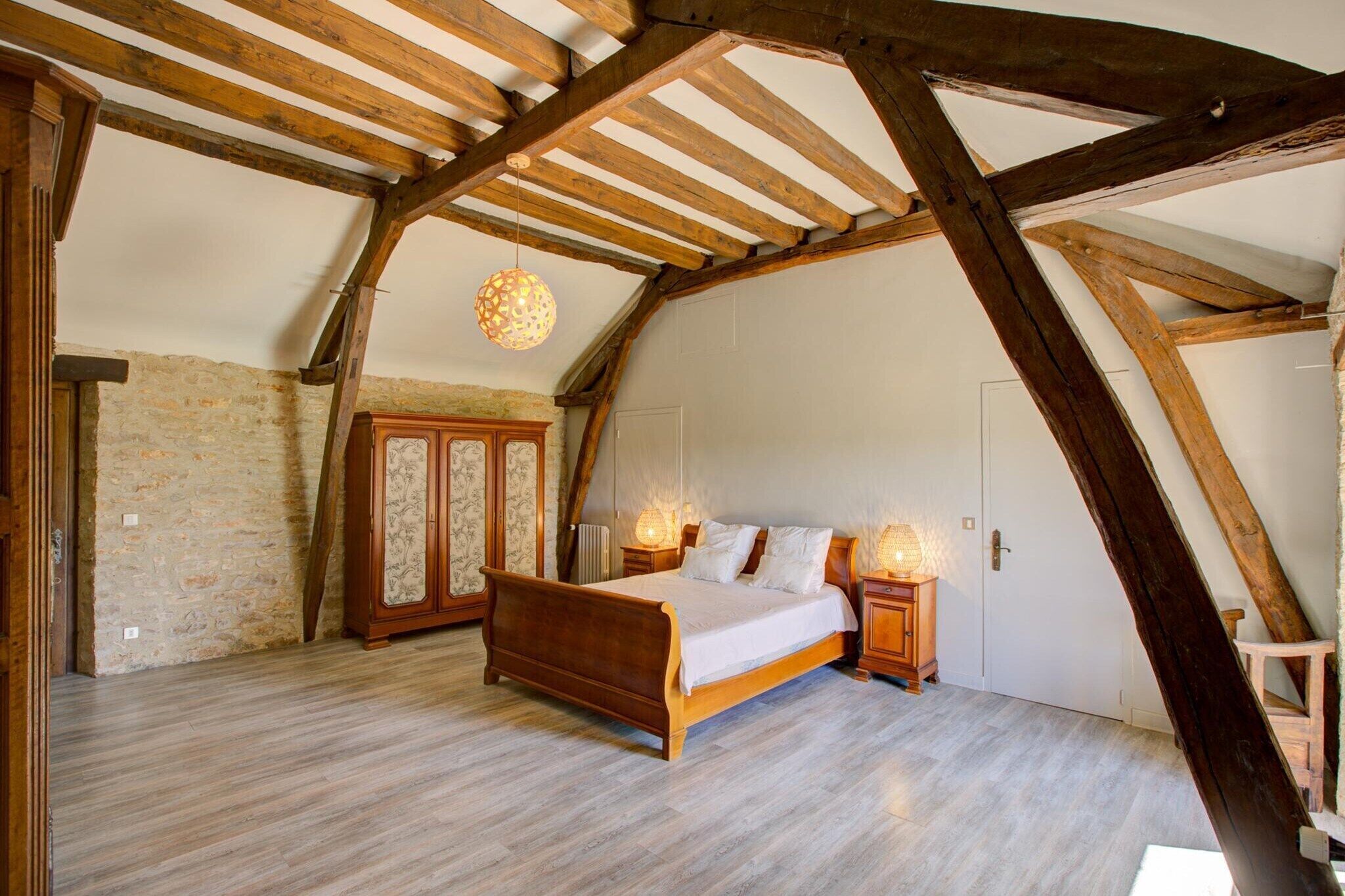 Une chambre avec un plafond en bois, un lit, une armoire et un luminaire suspendu.