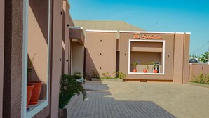 A building with a sign reading 'The Evolution' and a paved walkway with potted plants. - THE EVOLUTION HOTEL (Gombe)