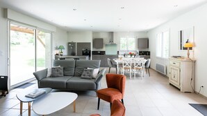 Una sala de estar moderna con un sofá gris, una mesa de centro y un comedor con una mesa y sillas blancas.