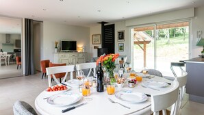 Un coin repas avec une table ronde dressée pour quatre personnes, entourée de chaises, et une cuisine en arrière-plan.