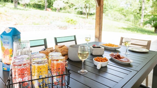Una mesa colocada al aire libre con comida, bebidas y conservas de frutas.