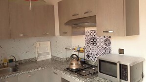 Eine Küche mit Granit-Arbeitsplatten, einem Gasherd, einem Wasserkocher, einer Mikrowelle und einer roten Hängelampe.