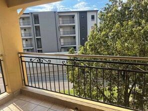 A balcony with a metal railing, a tiled floor, and a view of a multi-story building with balconies. - Spacious Apartment Near Gautrain, Gallagher & MOA (Midrand)