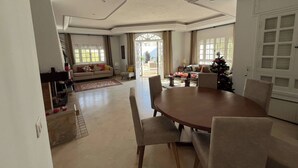 A spacious living room with a large dining table, a sofa, and a Christmas tree.