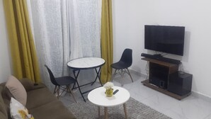 Olohuoneessa on sohva, kaksi nojatuolia, pieni pöytä, televisio ja kaiutinjärjestelmä.