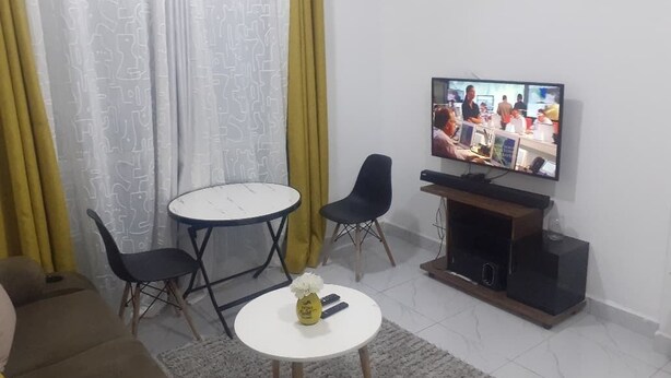Olohuone, jossa on televisio, pieni pöytä, kaksi tuolia ja sohva.