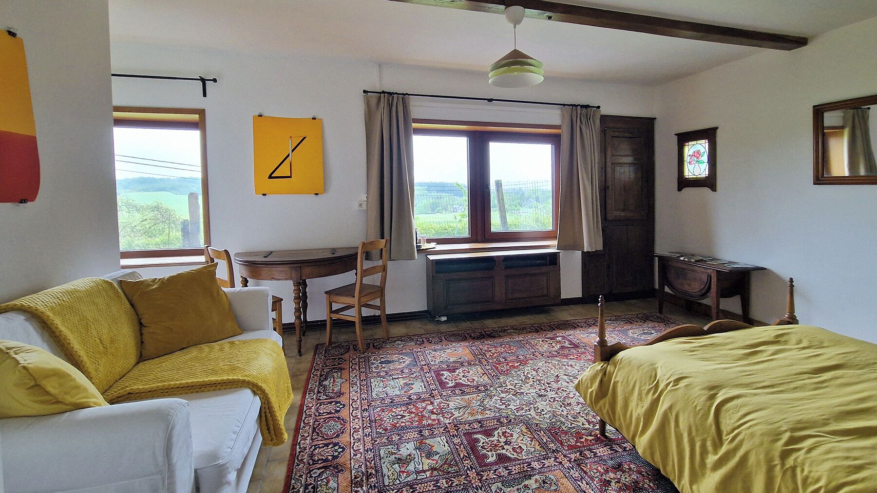 Une pièce comprenant un lit, un bureau, une chaise, une fenêtre avec des rideaux et un tapis à motifs.