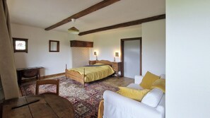 A bedroom with a bed, bedside tables, a chair, a sofa, a desk, and a window with a view. - Les herbes folles de Oizy, bed and breakfast with terrace in the Ardennes. (Oizy)