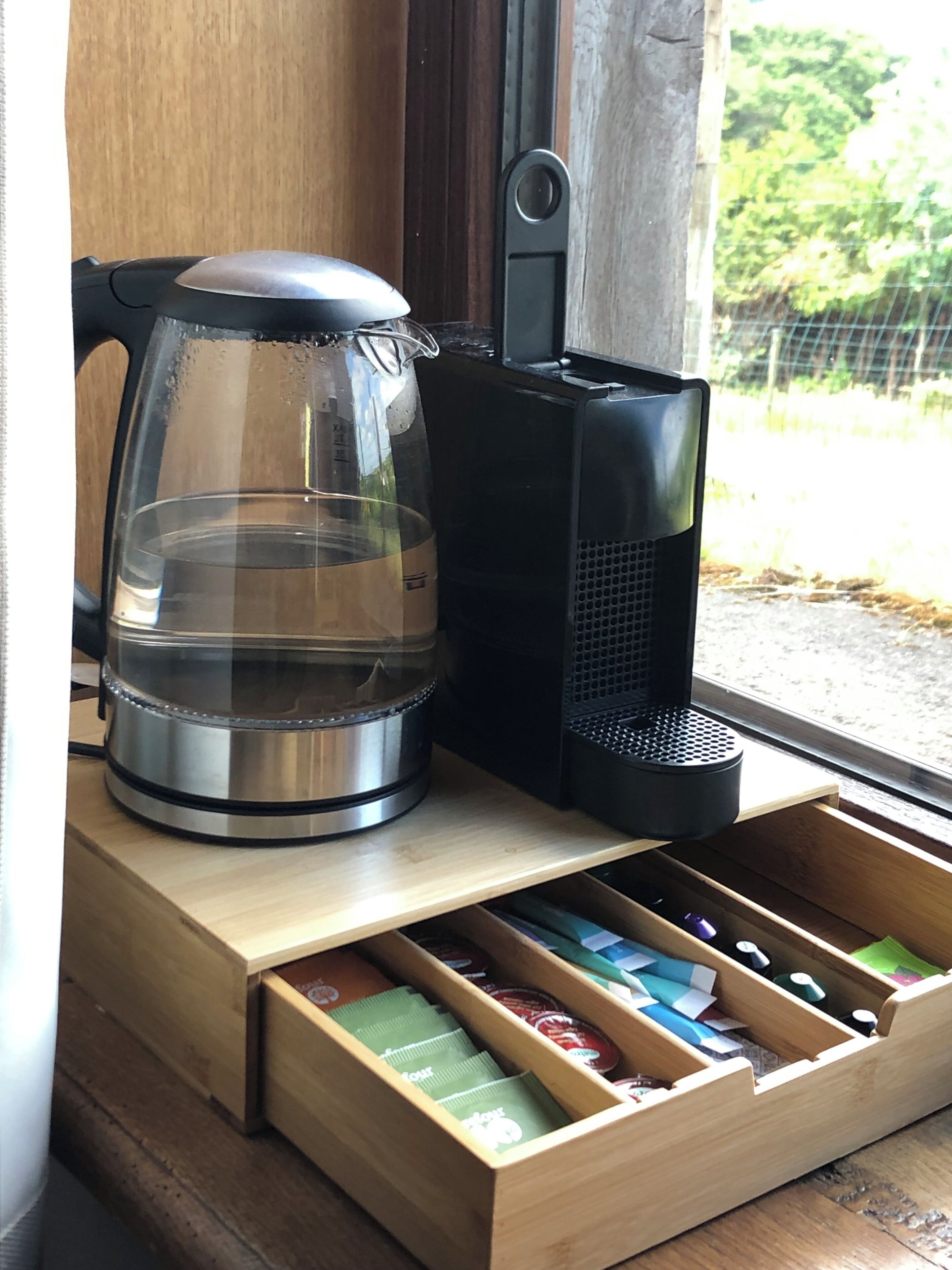 A coffee maker, a glass carafe, and a drawer with tea bags.