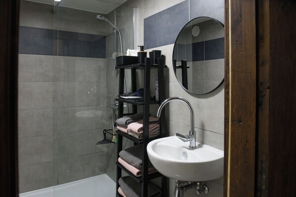 A modern bathroom with a shower, a sink, a mirror, and a towel rack.