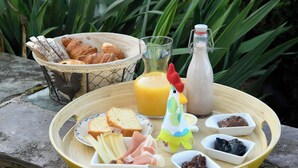 A breakfast setup with bread, pastries, cheese, ham, and a drink on a wooden table. - Les herbes folles de Oizy, bed and breakfast with terrace in the Ardennes. (Oizy)