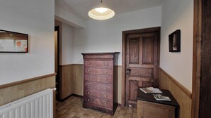A hallway with a wooden dresser, a door, and a radiator. - Les herbes folles de Oizy, bed and breakfast with terrace in the Ardennes. (Oizy)