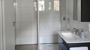 Un bagno moderno con doccia, lavandino e specchio.