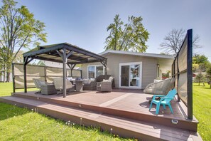 A covered outdoor deck with seating, a pergola, and a screened area.