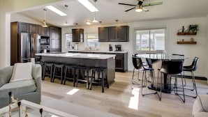 Una cocina moderna con una isla central, taburetes de bar y una mesa de comedor con sillas.