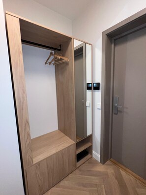A walk-in closet with wooden shelving, a mirror, and a door. - Kalpaka Residence Apartment  (Rīga)
