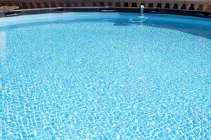 Ein klares, blaues Schwimmbecken mit einer gefliesten Kante und einem sichtbaren Wasserspiel.
