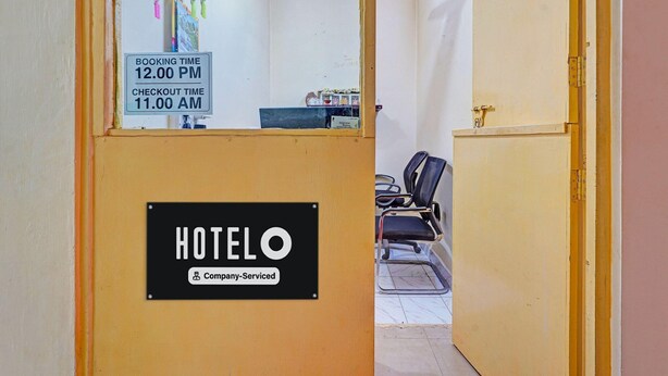 A hotel reception area with a booking time sign, a reception desk, and a seating area with chairs. - Hotel O Delmon Residency (Chennai)