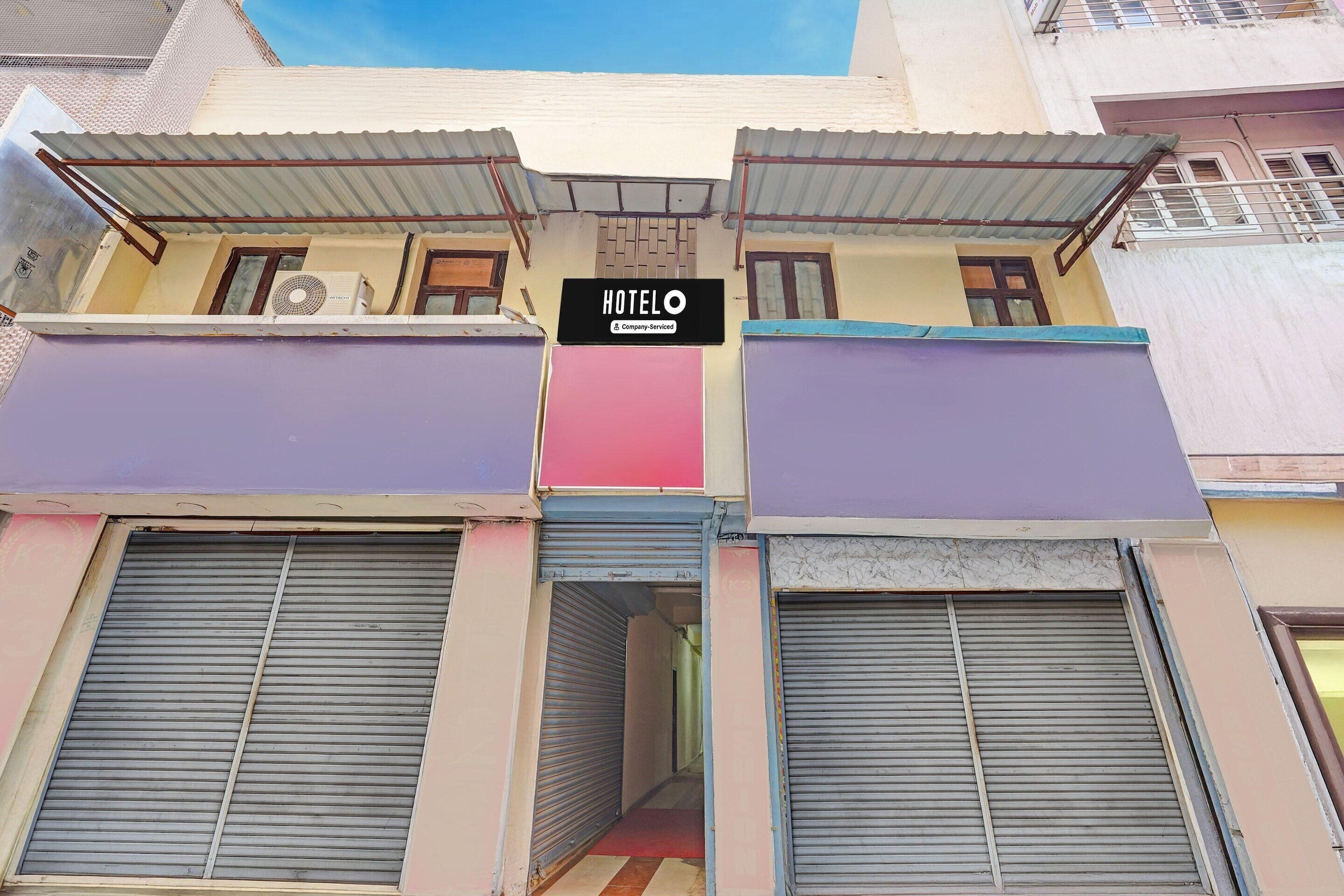 A hotel with a signboard, closed shutters, and a visible air conditioning unit.