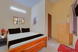 Een slaapkamer met een bed, een houten garderobe, een rode stoel en wanddecoratie.