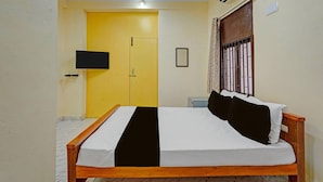 A bedroom with a bed, a television on the wall, a door, and an air conditioning unit. - Hotel O Delmon Residency (Chennai)