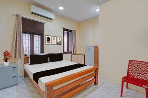 Een slaapkamer met een bed, een bureau, een stoel en een airconditioner.