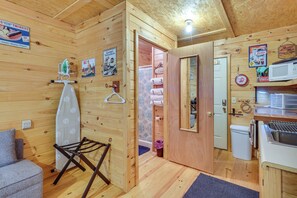 Ein Holzblockhaus-Interieur mit Küchenzeile, einem Wäscheständer, einem Spiegel und einer Tür zu einem Badezimmer.