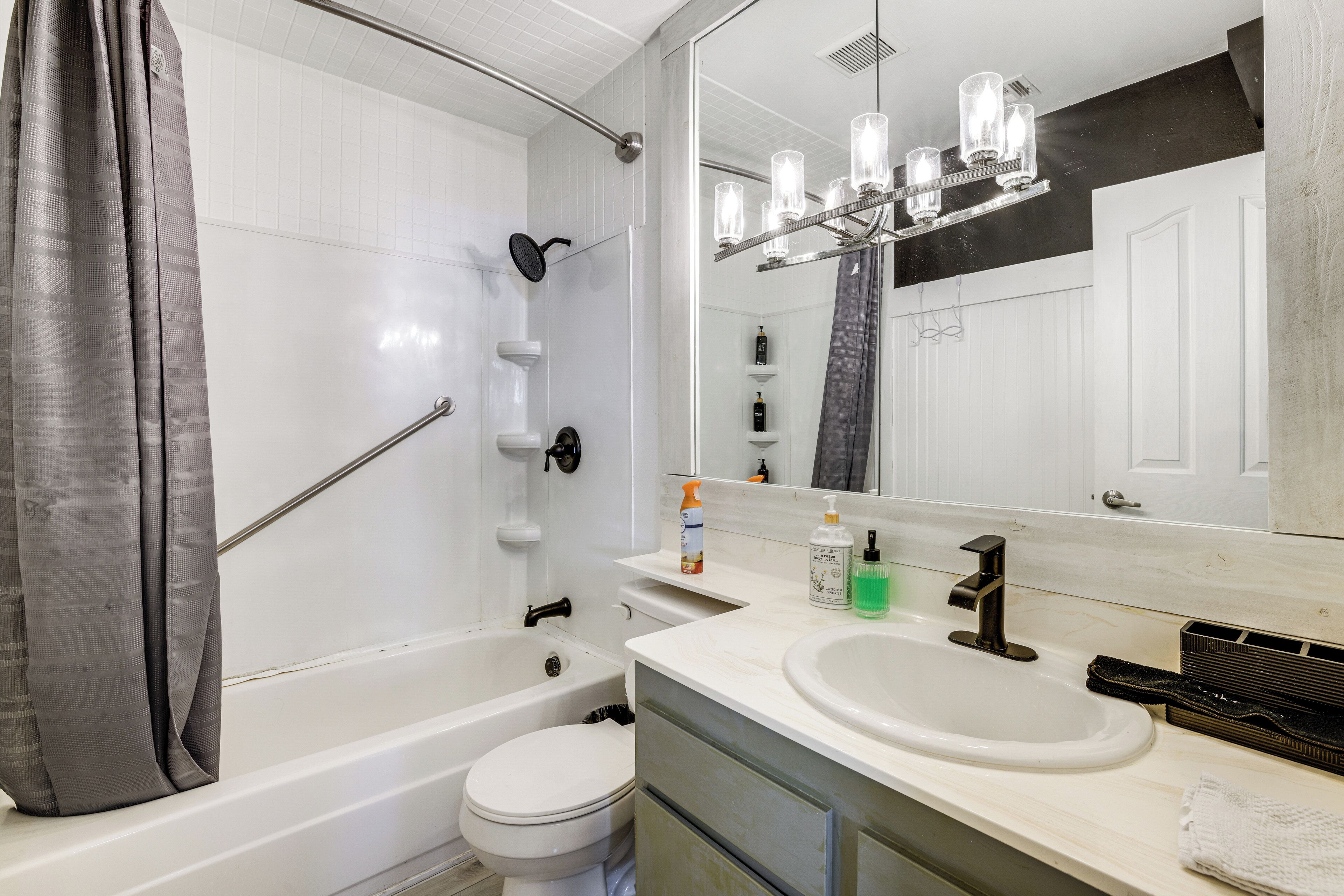 A bathroom with a bathtub, toilet, sink, and a mirror.