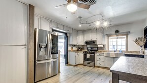 Eine moderne Küche mit Edelstahlgeräten, Holzböden und einem Deckenventilator.