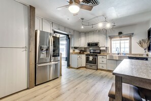 Eine moderne Küche mit Edelstahlgeräten, Holzböden und einem Deckenventilator.