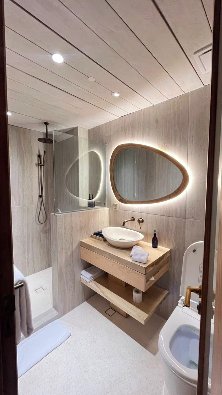 Un bagno moderno con un mobile bagno in legno, uno specchio rotondo, una doccia e un water.