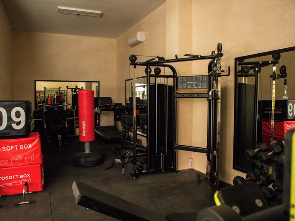Un gimnasio con equipo de levantamiento de pesas, un saco de boxeo y un espejo.
