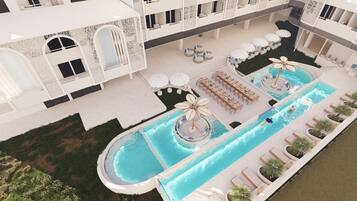 A rooftop pool with lounge chairs, umbrellas, and a circular water feature.