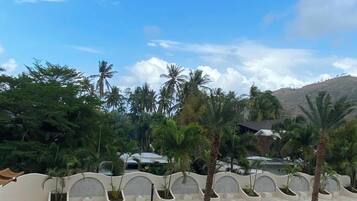 A resort pool area with a circular water feature, palm trees, and a view of a hilly landscape.