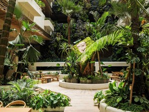 An indoor garden with a variety of plants, seating areas, and a central water feature.