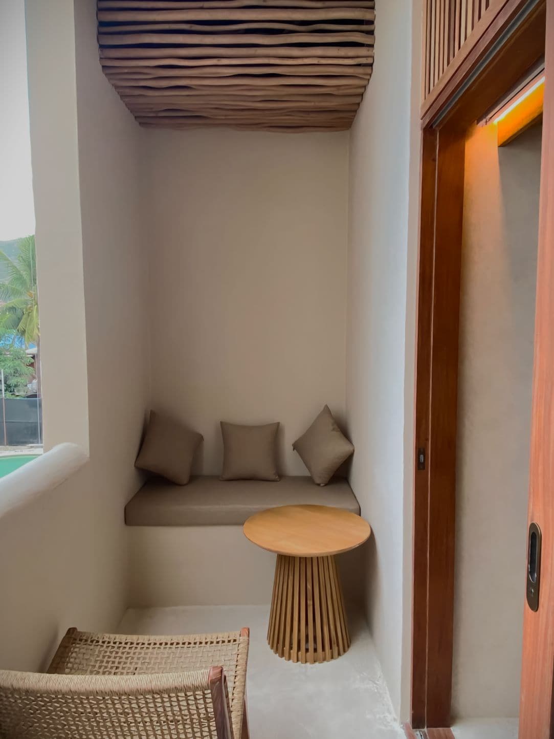 A corner room with a built-in bench, a small round table, and a wicker chair.