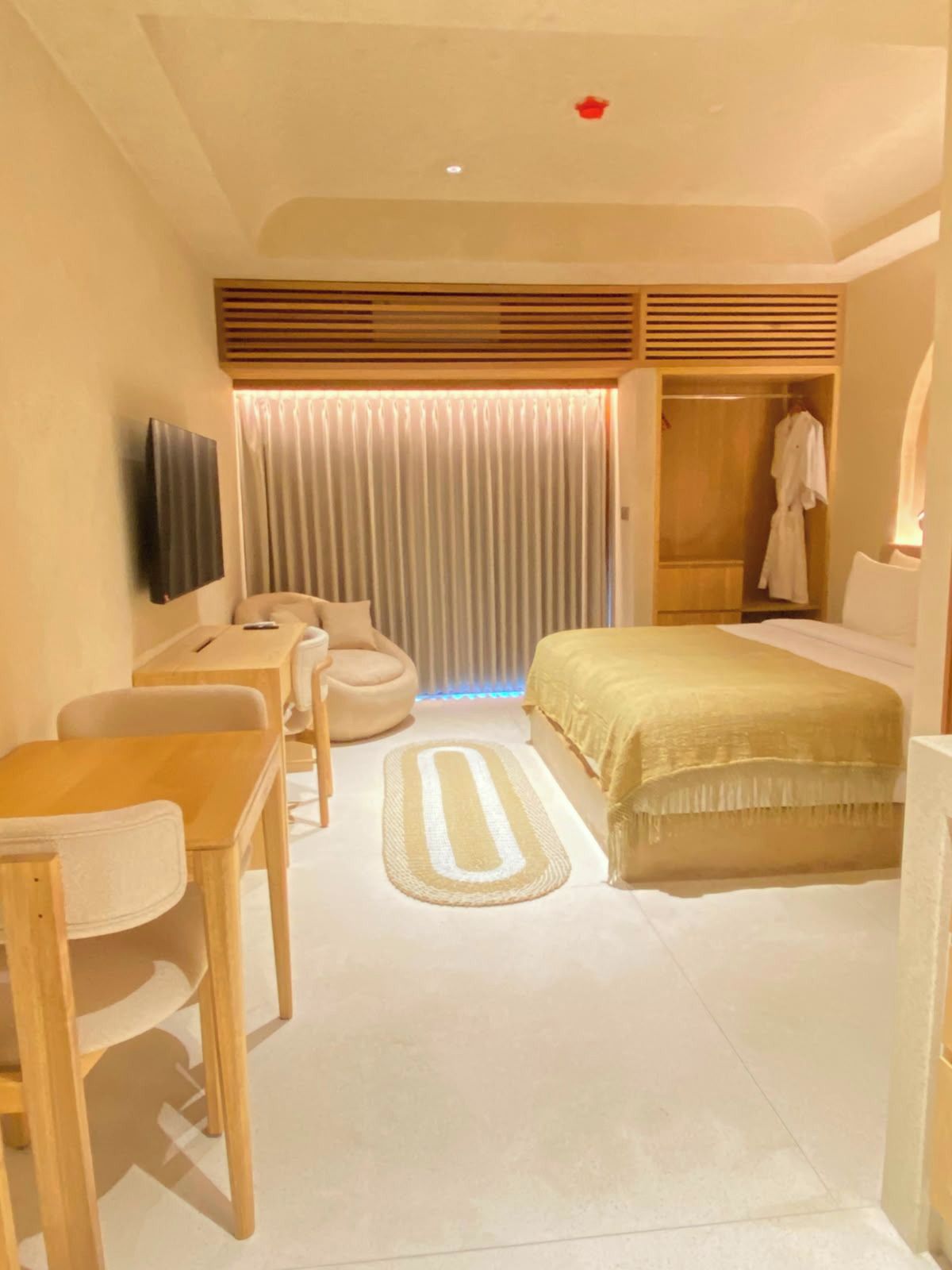 Une chambre d’hôtel comprenant un lit, un bureau, une chaise, une télévision et une armoire.