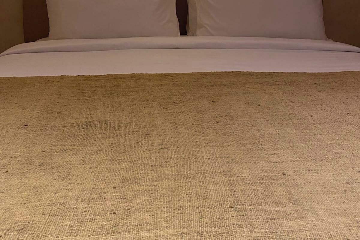 Una cama con cabecera de diseño arqueado y dos lámparas de pared.