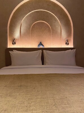 A bed with a headboard featuring an arched design and two wall-mounted light fixtures.