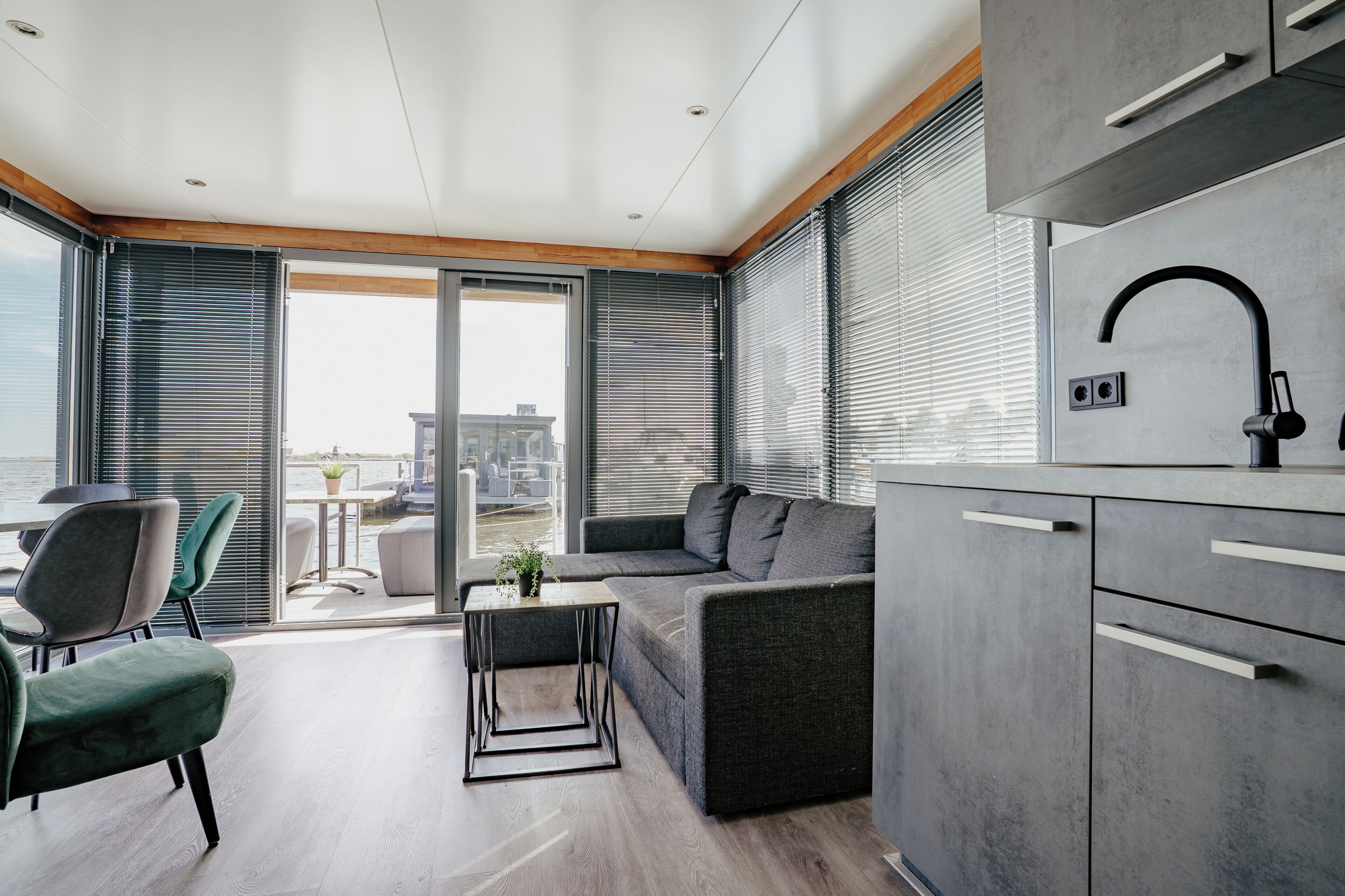 A modern kitchen with grey cabinets, a black faucet, and a dining area with a table and chairs.