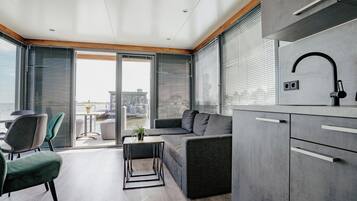 A modern kitchen with grey cabinets, a black faucet, and a dining area with a table and chairs.