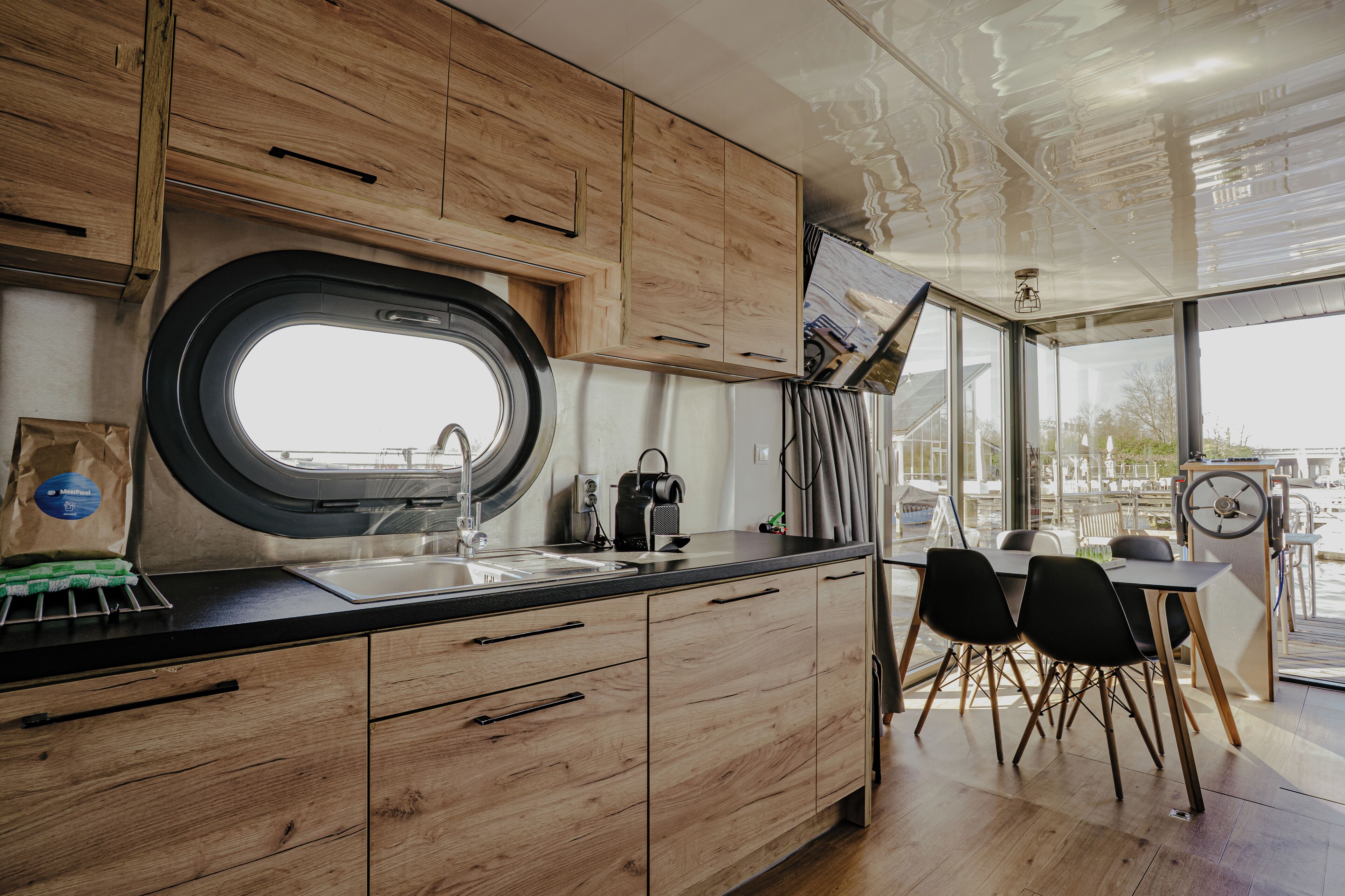 Een moderne keuken met houten kastjes, een zwart aanrecht en een raam.