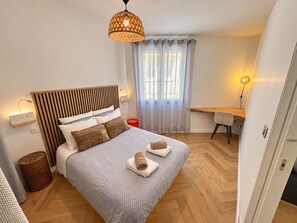 Ein Schlafzimmer mit einem Bett, einem Nachttisch, einer Lampe und einem Schreibtisch mit Stuhl.