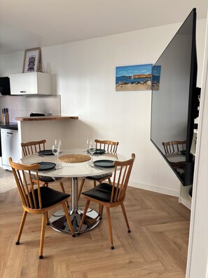 A dining area with a round table, four wooden chairs, and a white cabinet in the background. - L'écrin Sétois - T2 Air-conditioned - Walking distance to train station and center of Sète (Sète)