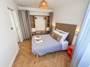 A bedroom with a bed, bedside table, wardrobe, and a hanging light fixture. - L'écrin Sétois - T2 Air-conditioned - Walking distance to train station and center of Sète (Sète)