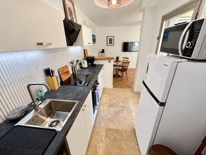 A compact kitchen with a microwave, sink, and a small dining area. - L'écrin Sétois - T2 Air-conditioned - Walking distance to train station and center of Sète (Sète)