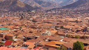 A cityscape with a dense urban layout, a prominent church, and surrounding mountains. - Sueños de San Blas Hostel (Cusco)