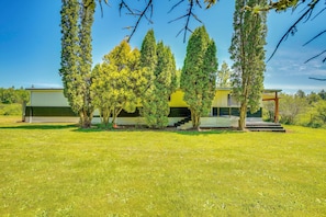 A modern house with a green lawn, a covered porch, and a staircase leading to a deck. - Stunning View! Peaceful Family Home w/ Yard in Roy (Roy)